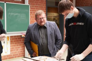 Bernd Wölbern (links) lässt sich von einem Schüler ein Gewerk im Bereich Holz zeigen.